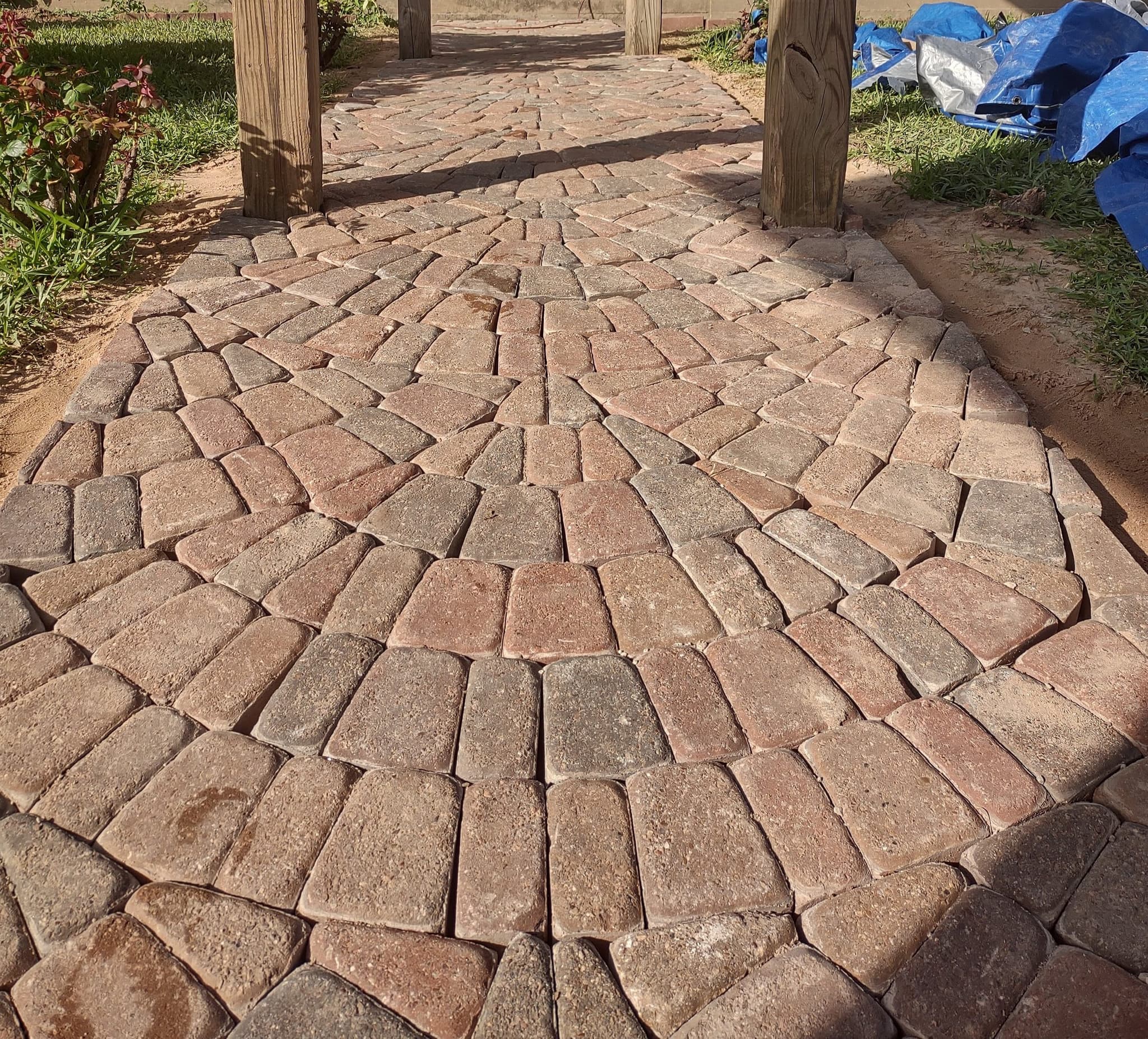 Close detail of a tumbled cobblestone paver walkway laid in a fan pattern, set on a compacted sand base.