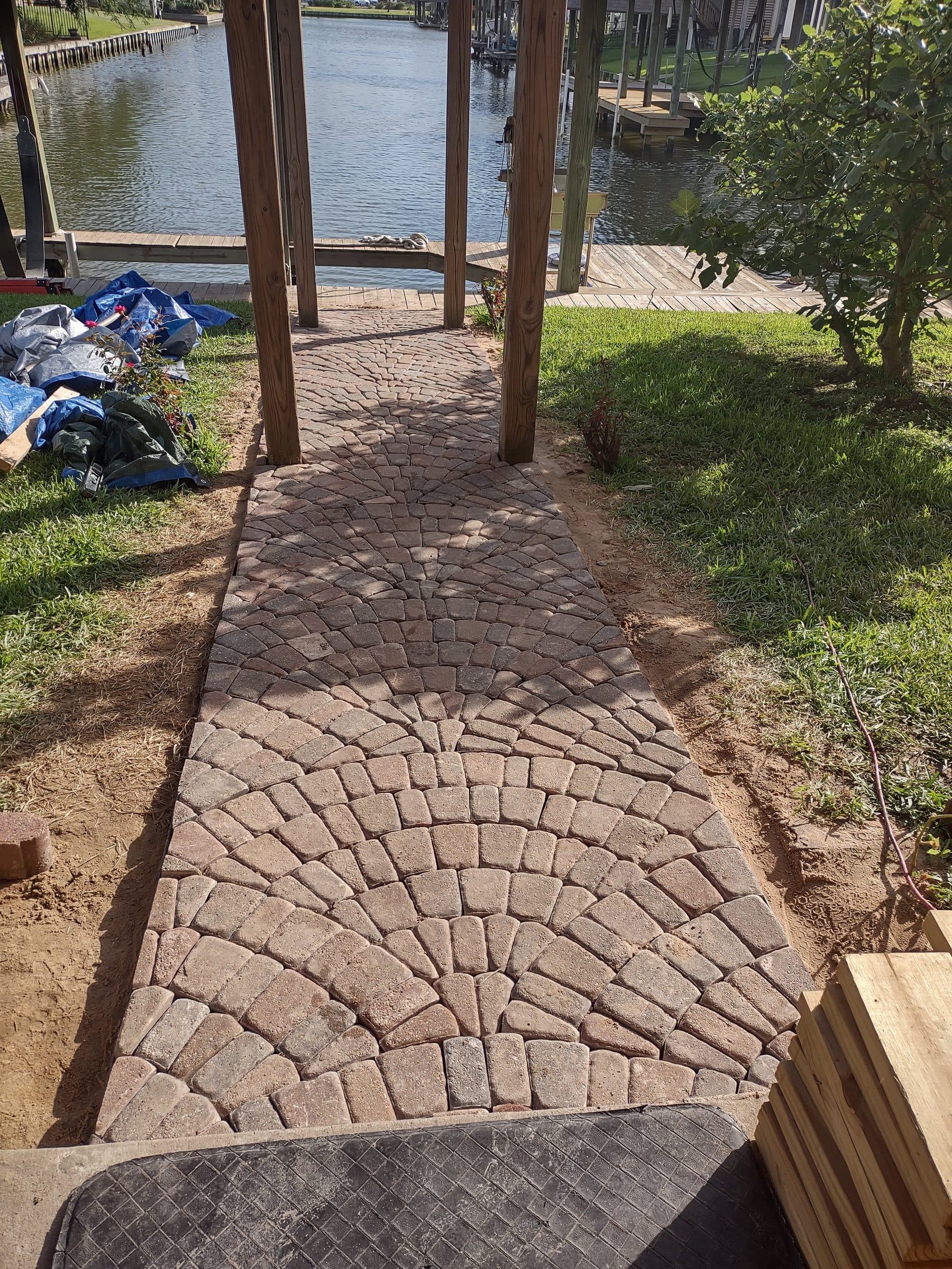 A tumbled cobble walkway mid-installation, showing the screeded base and fan-pattern layout.
