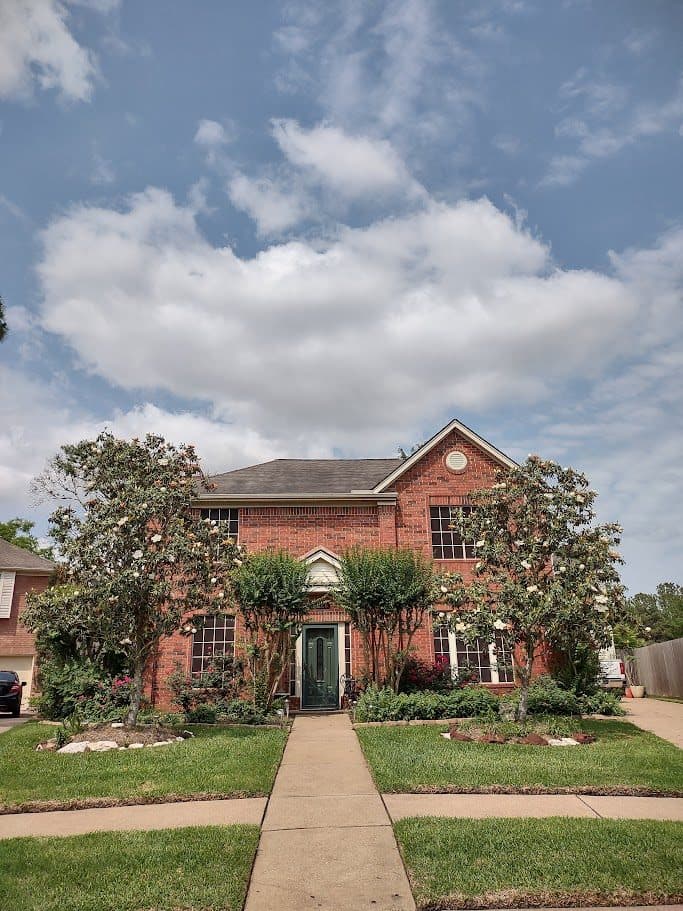 Trimmed foundation shrubs and freshly cut, mulched beds at a traditional brick home.