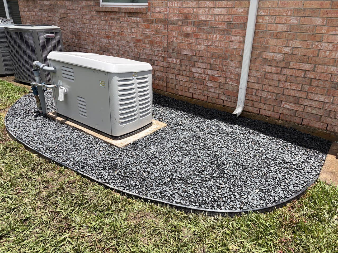 A shaped, steel-edged gravel pad built around a standby generator.