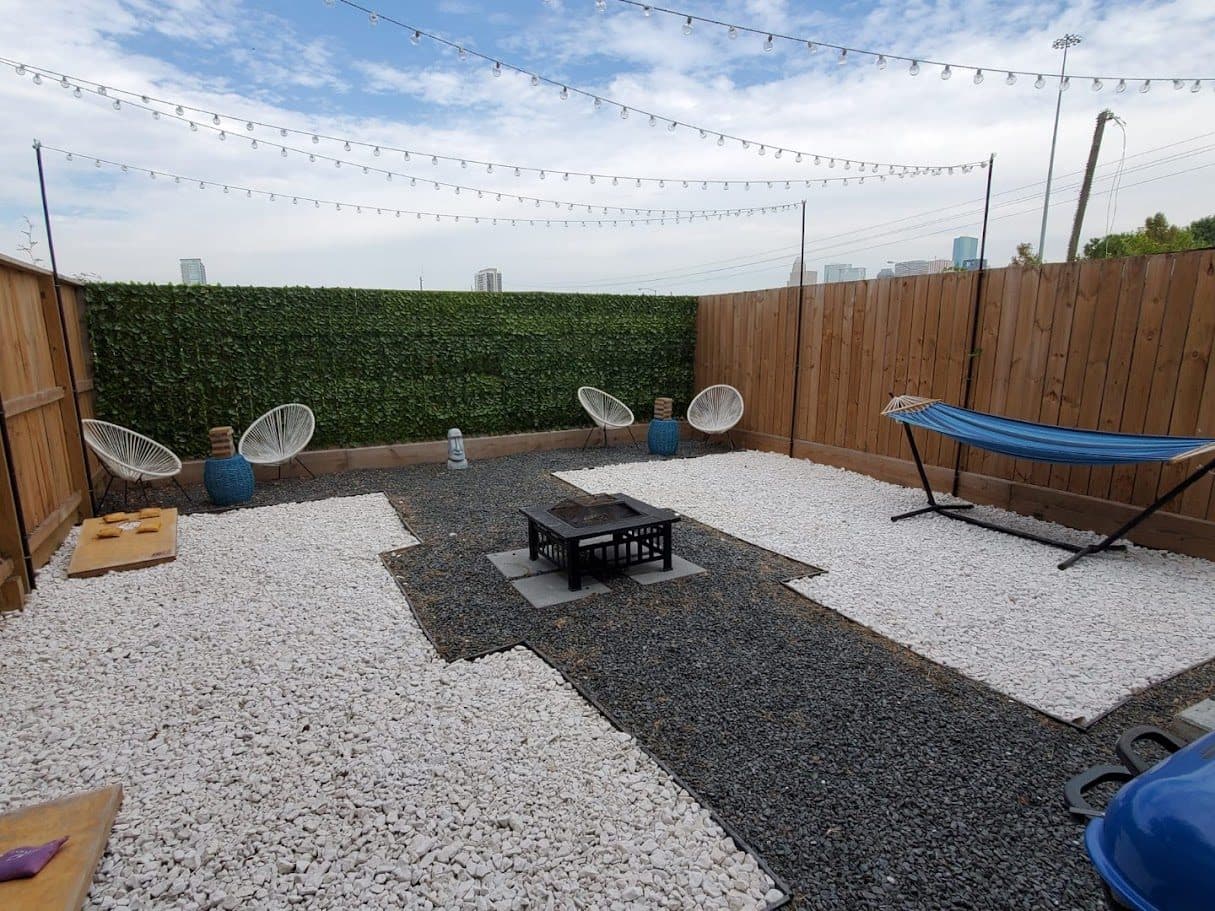 A decomposed-granite patio with hammock, string lighting and privacy screening.