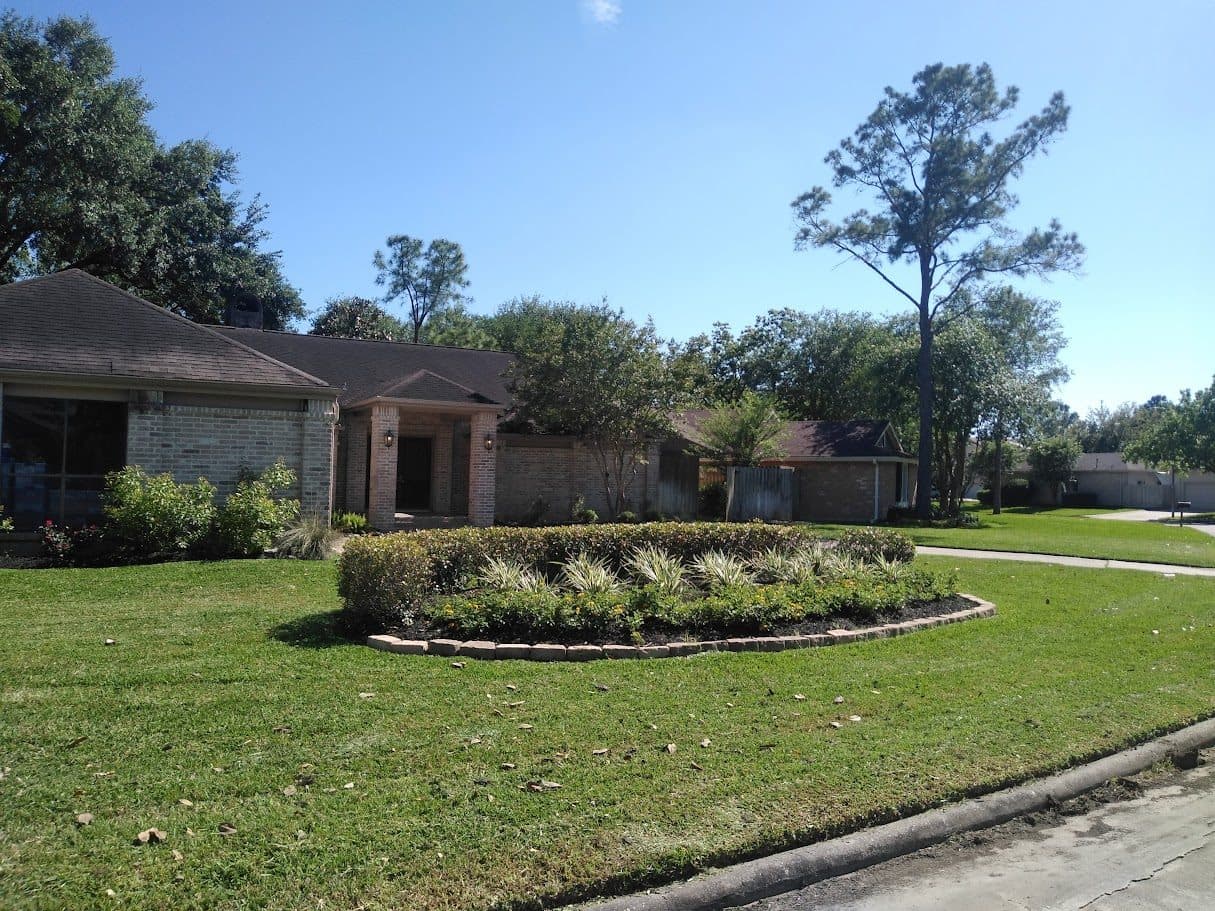 A shaped island bed set into a wide, evenly maintained front lawn.