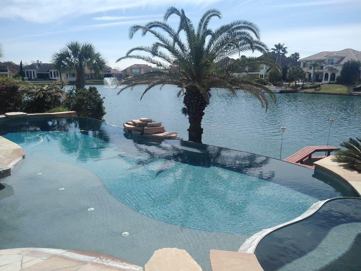 A negative-edge pool and palm planting overlooking the water in a Houston lake community.